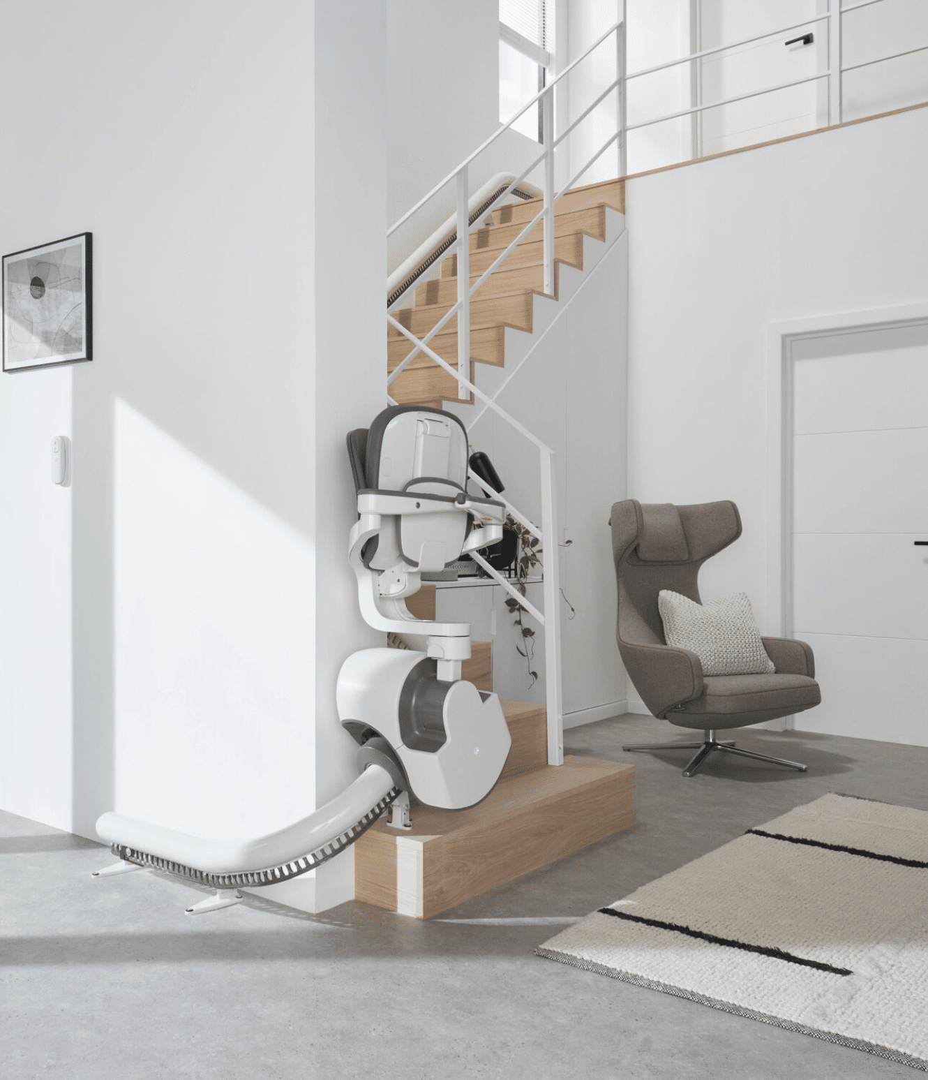Prestige Flow X stairlift in its foldaway position at the bottom of a curved staircase