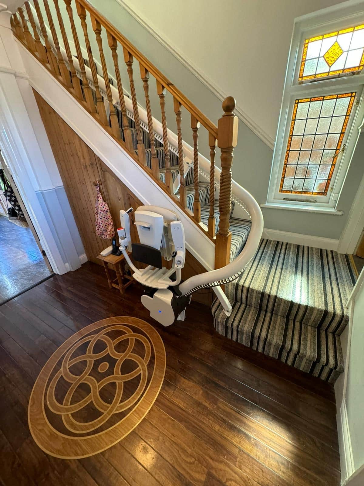 Curved stairlift in its foldaway position at the bottom of stairs