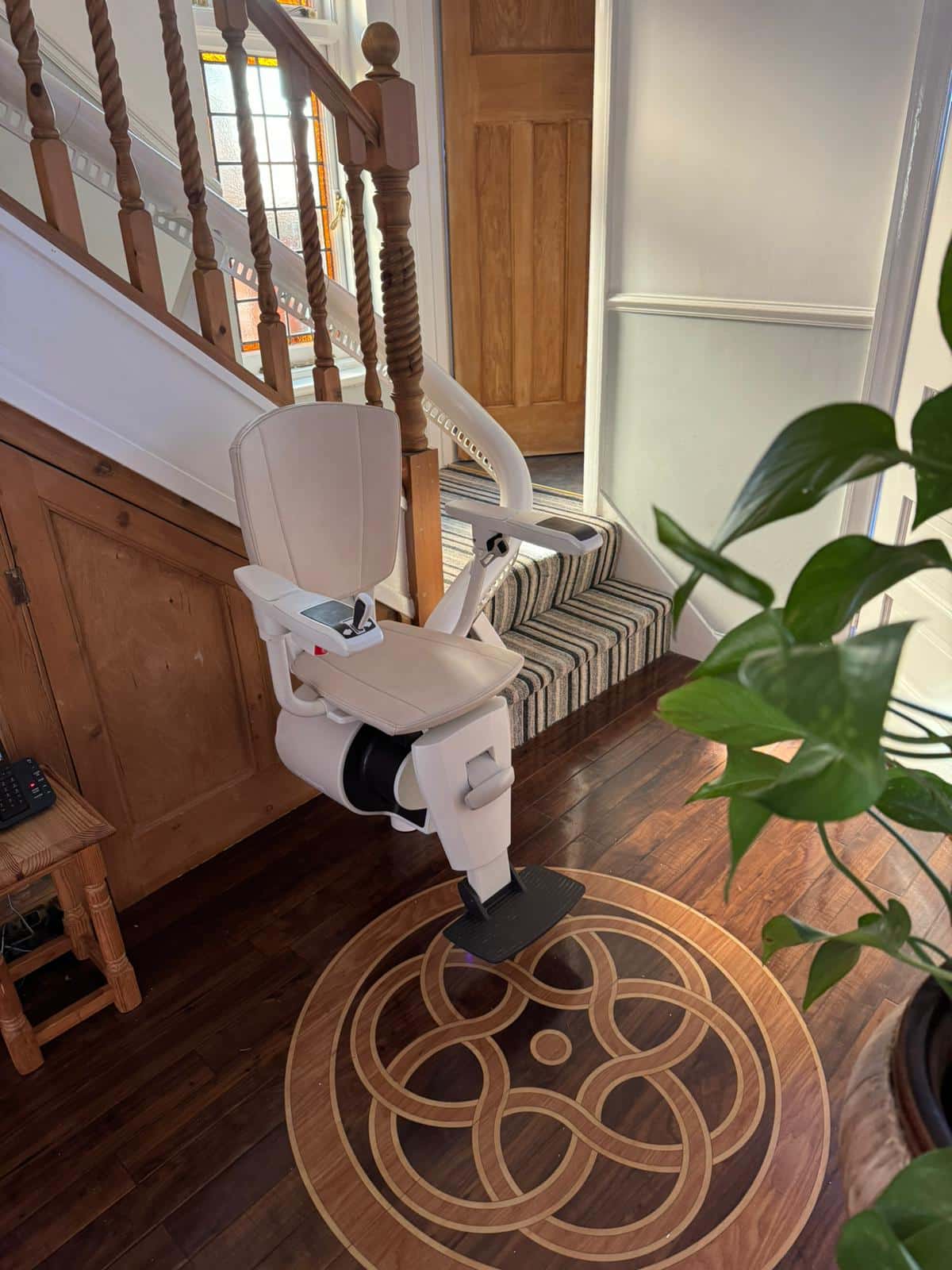 Curved stairlift in its ready position at the bottom of curved staircase