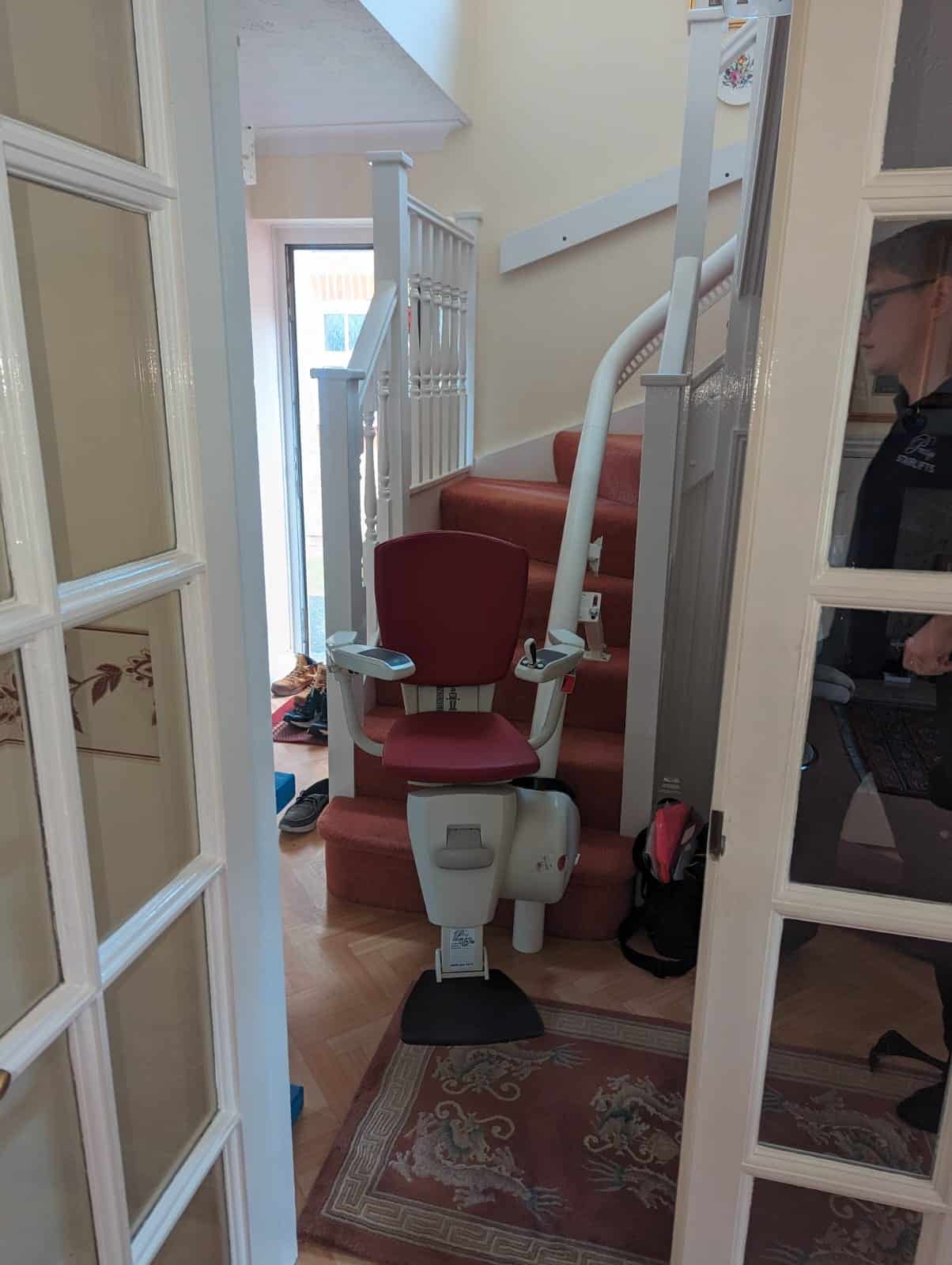 Flow 2a stairlift with red upholstered seat at the bottom of the stairs