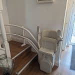 Curved stairlift in foldaway position at the bottom of stairs