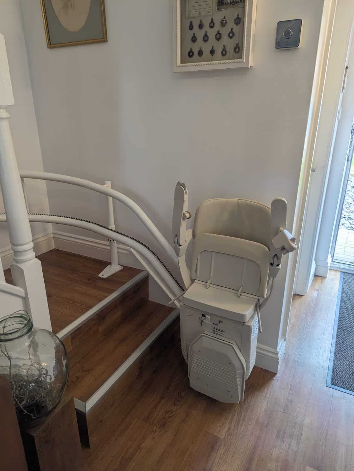 Curved stairlift in foldaway position at the bottom of stairs