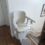 Stairlift in ready position at the top of a curved staircase on a twin rail