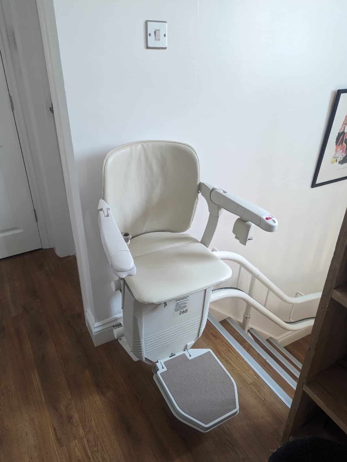 Stairlift in ready position at the top of a curved staircase on a twin rail