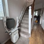 Platinum stairlift with grey seat in folded position at the bottom of the stairs demonstrating the clearance on the stairs