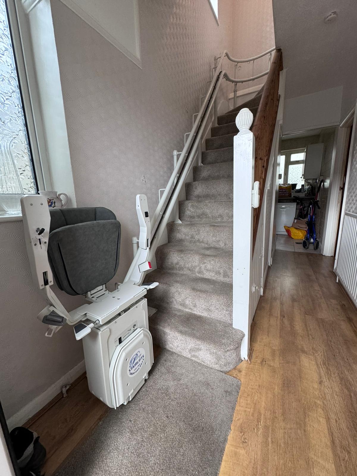 Platinum stairlift with grey seat in folded position at the bottom of the stairs demonstrating the clearance on the stairs