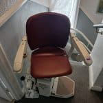 Stairlift at the top of the stairs with red seat