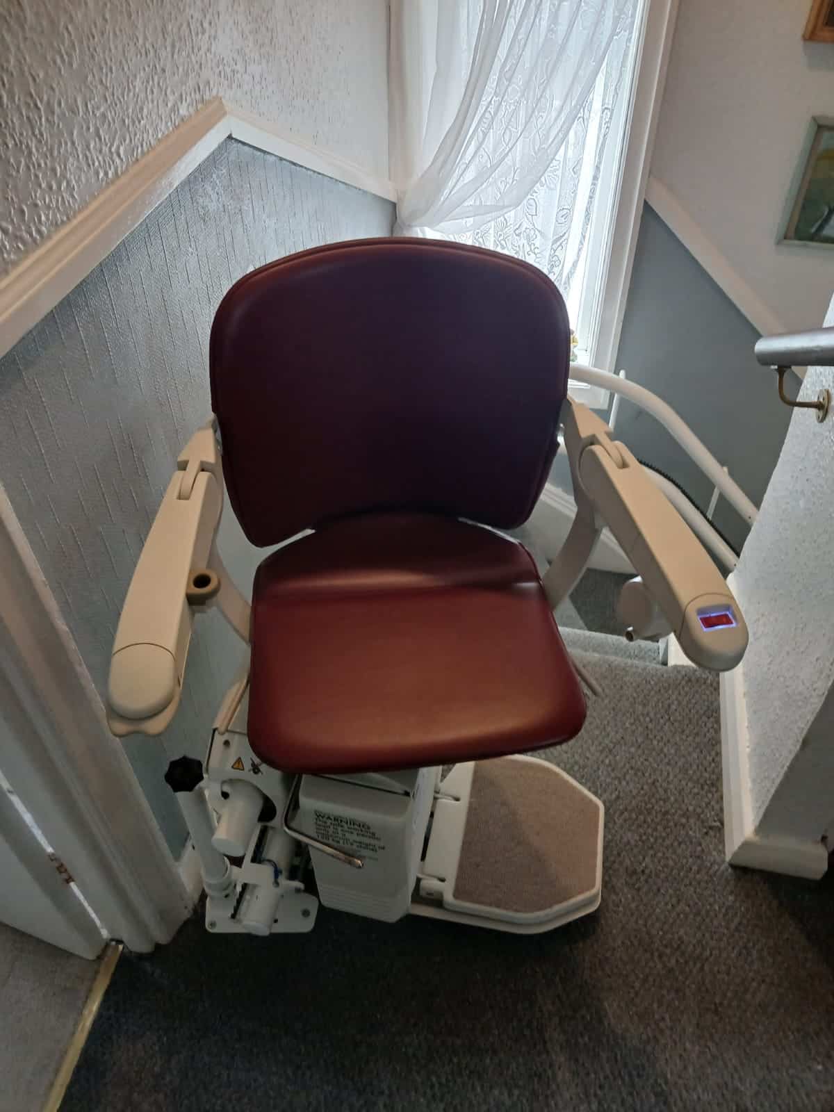 Stairlift at the top of the stairs with red seat