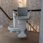 Otolift stairlift with grey seat at the top of the stairs clearly illustrating the rail