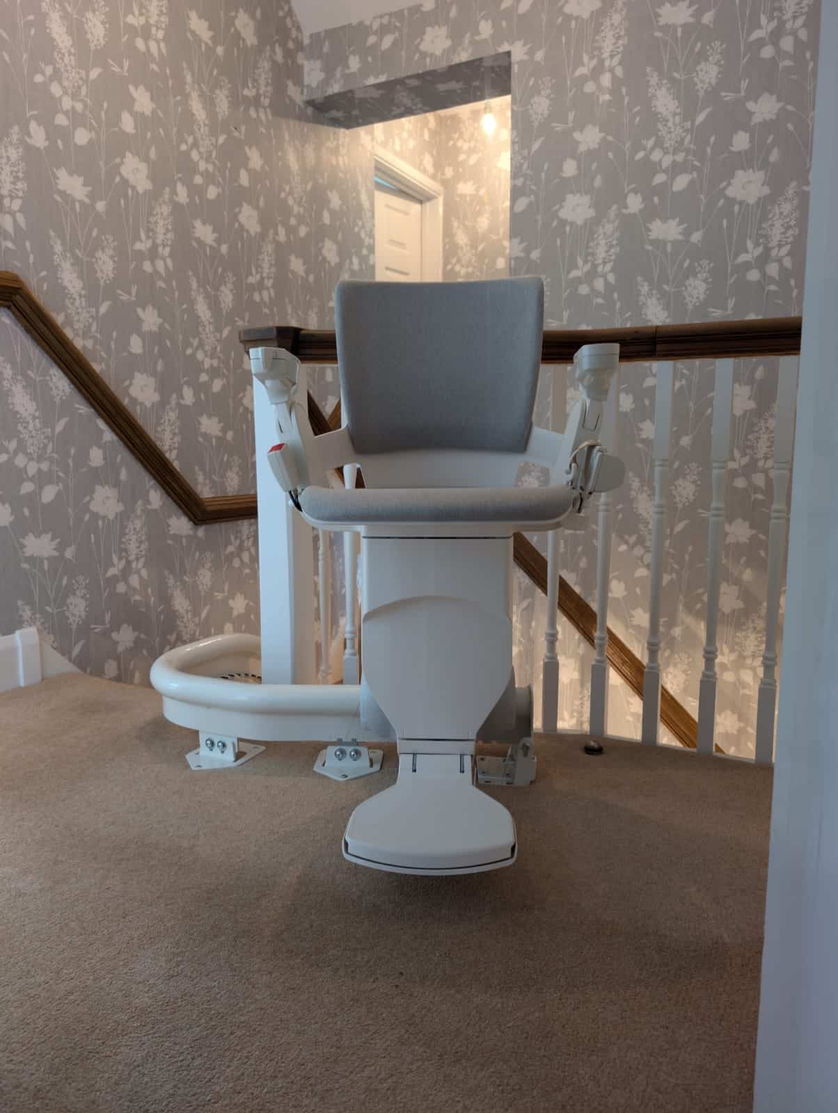 Otolift stairlift with grey seat at the top of the stairs clearly illustrating the rail
