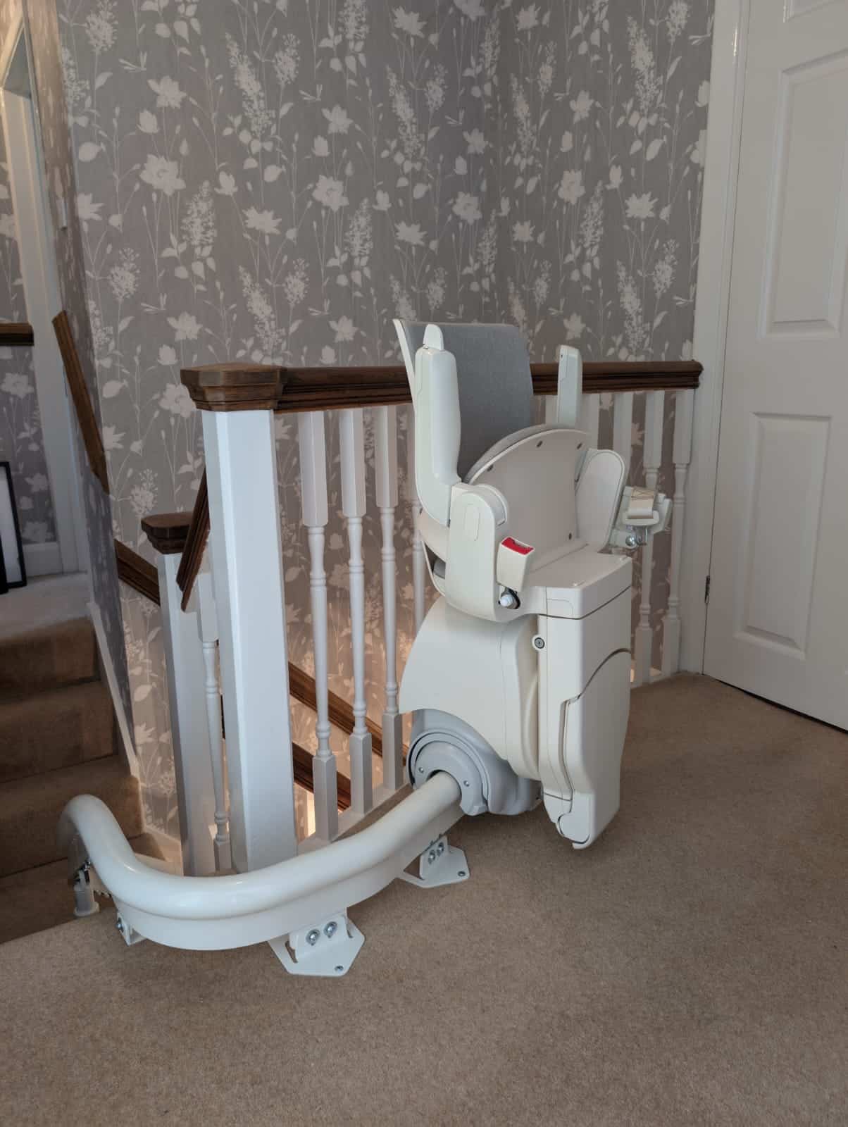 Otolift stairlift at the top of the stairs shown in its parked and folded position demonstrated from the side view