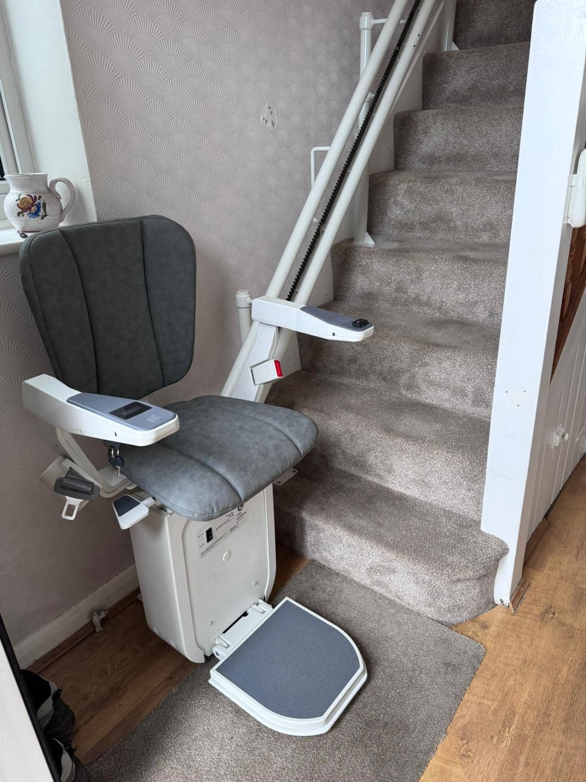 Platinum stairlift with grey seat in ready position clearly illustrating arm rest controls