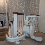 Otolift stairlift at the top of a curved staircase in its ready position
