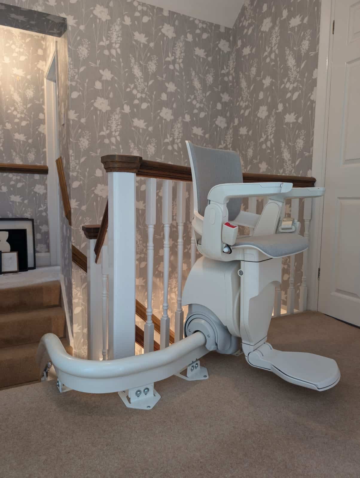 Otolift stairlift at the top of a curved staircase in its ready position