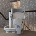 Otolift stairlift at the top of the stairs clearly demonstrating the seat in its folded up position