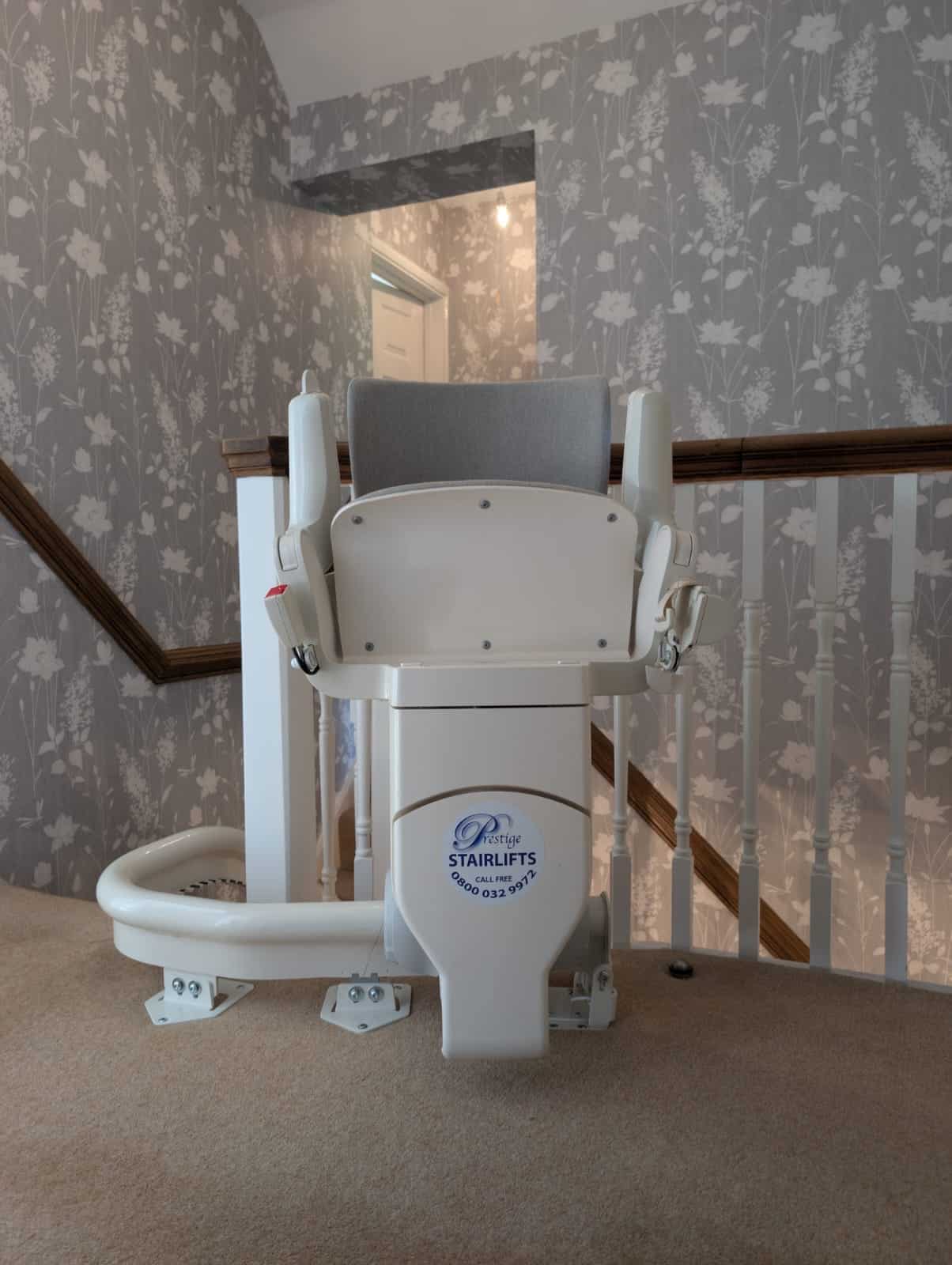 Otolift stairlift at the top of the stairs clearly demonstrating the seat in its folded up position