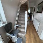 Platinum stairlift with grey upholstery in ready position at the bottom of the stairs