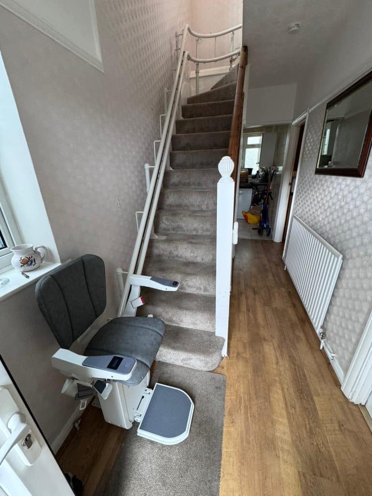 Platinum stairlift with grey upholstery in ready position at the bottom of the stairs