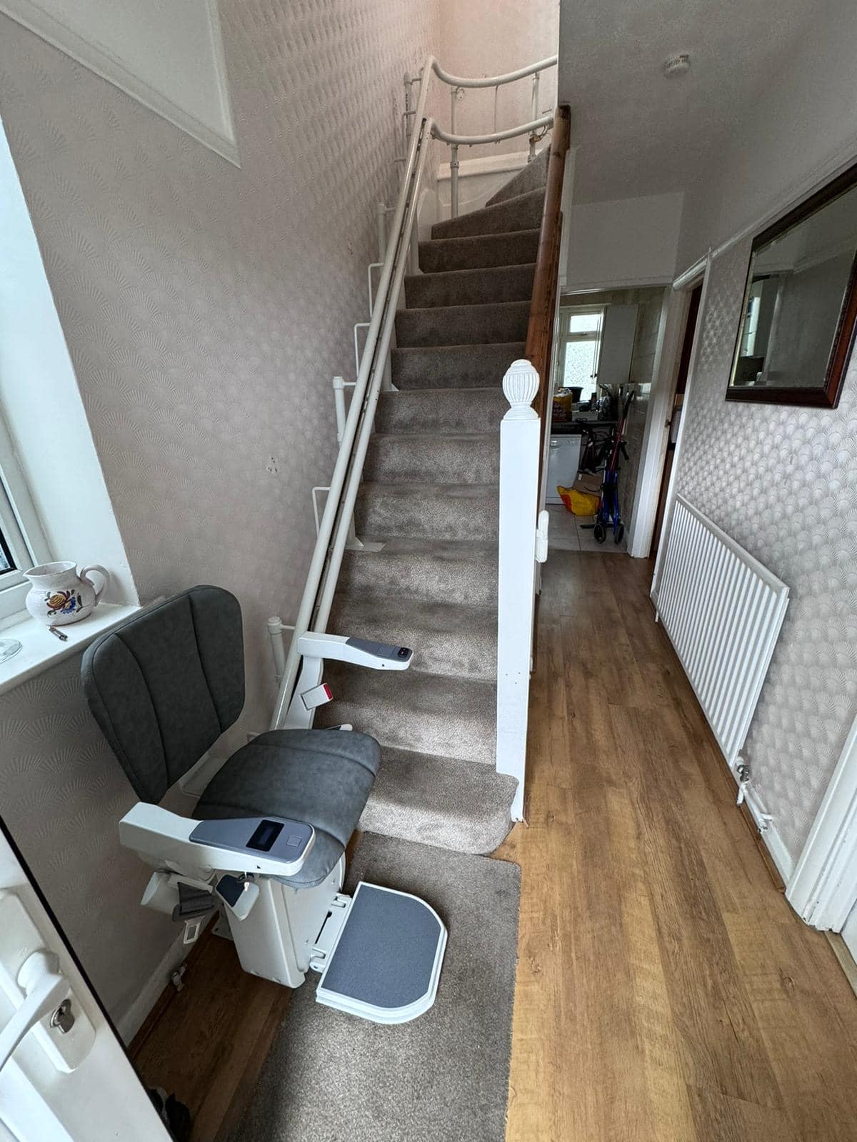 Platinum stairlift with grey upholstery in ready position at the bottom of the stairs
