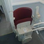 Stairlift with red seat in folded position