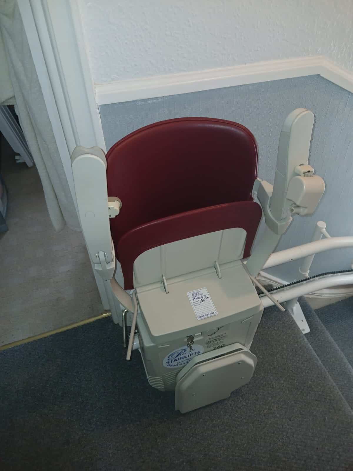 Stairlift with red seat in folded position