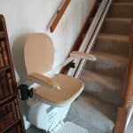 Straight stairlift in ready position at the bottom of a staircase
