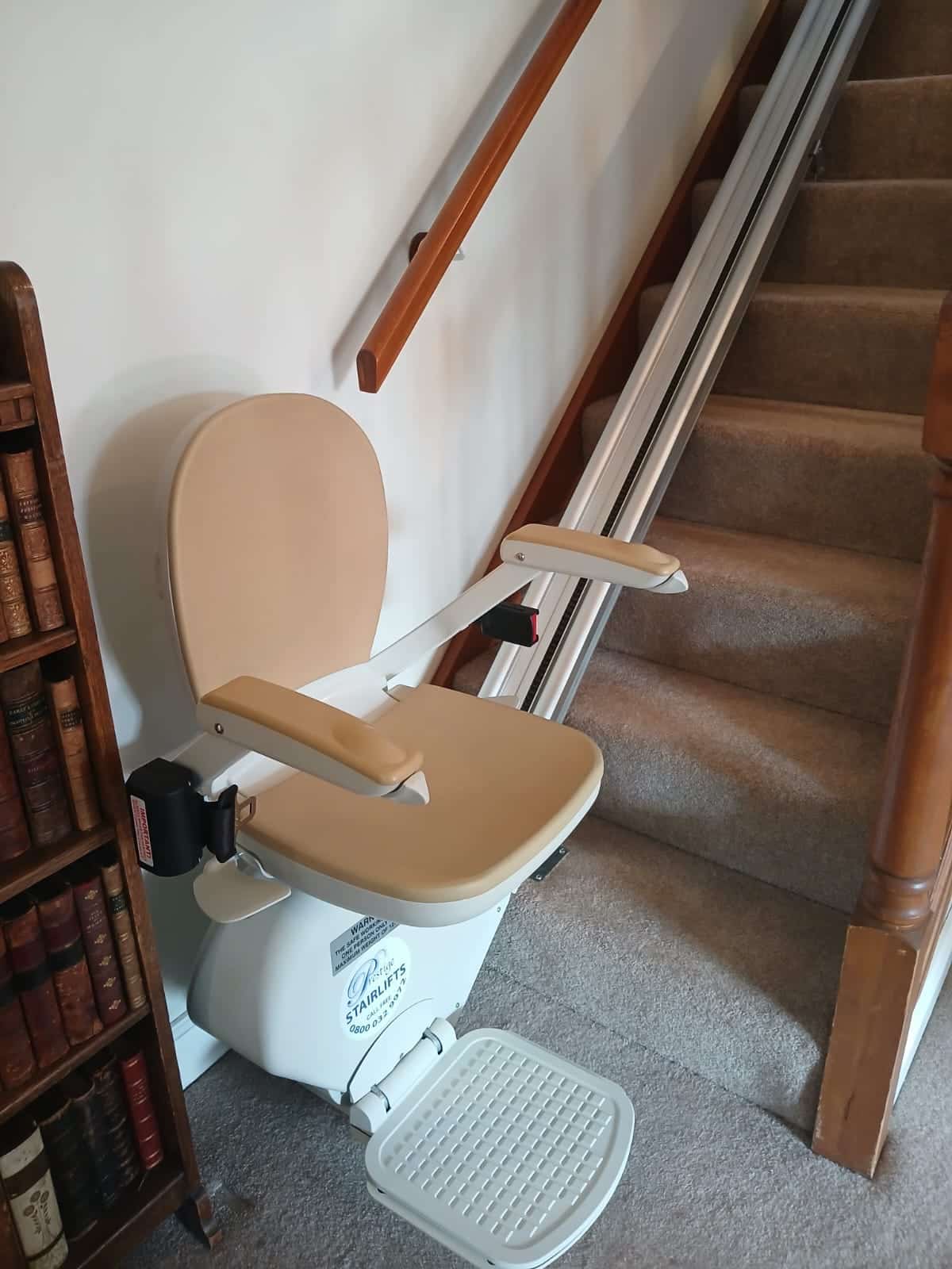 Straight stairlift in ready position at the bottom of a staircase