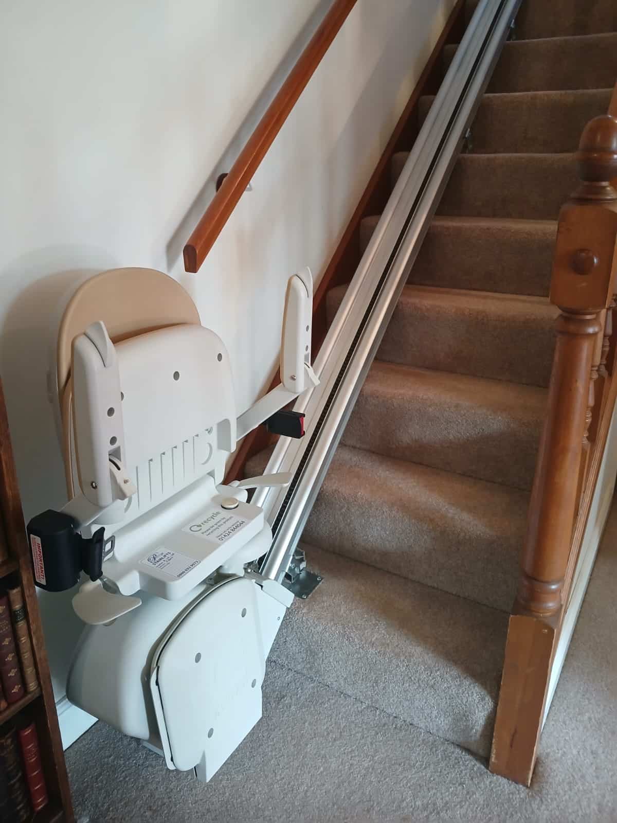 Stairlift in parked position at the bottom of a straight staircase