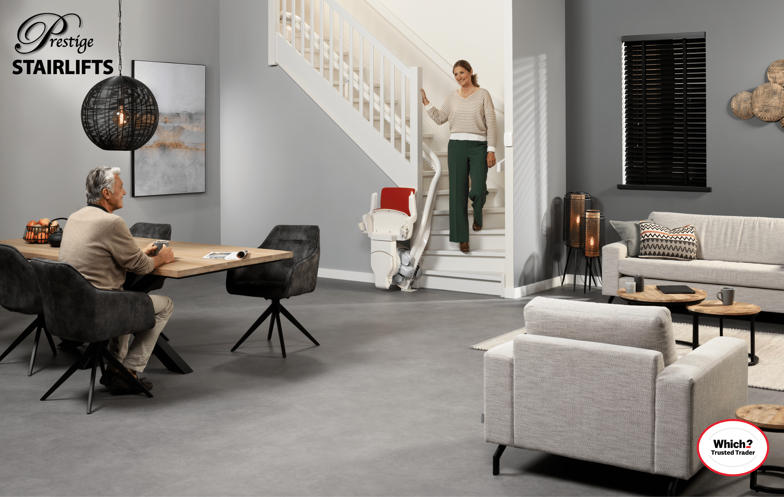 Otolift stair lift in parked position at the bottom of the stairs shown with lady walking past it coming down the stairs